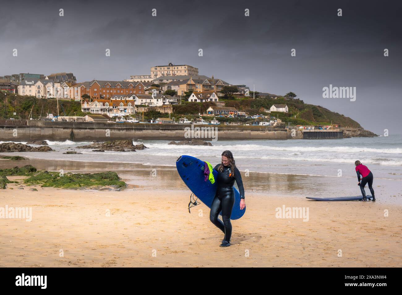 Eine Surferin, die ihr Surfbrett trug, nachdem sie am Towan Beach in Newquay in Cornwall in Großbritannien gesurft hatte. Stockfoto