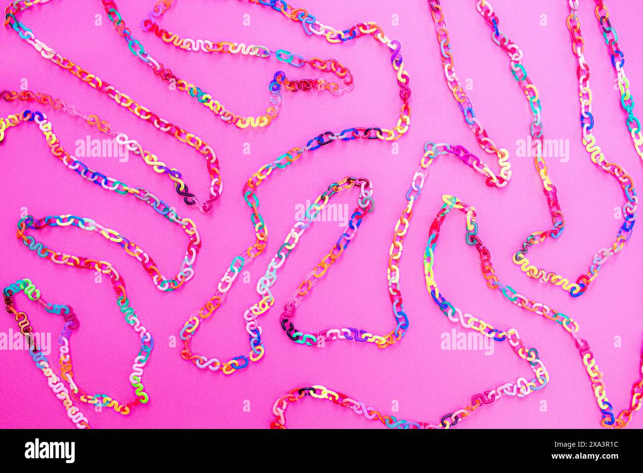 Retro 80er oder 90er Jahre farbenfroher Hintergrund aus Kunststoff-Kette verbindet Buchstaben als kurviges Labyrinth in allen Farben auf dem rosafarbenen Hintergrund, lebendige Farben Stockfoto