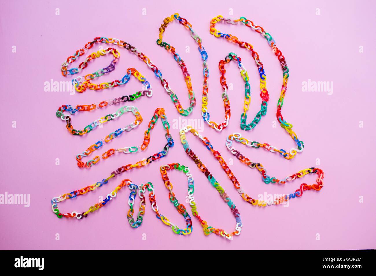 Retro 80er oder 90er Jahre farbenfroher Hintergrund aus Kunststoff-Kette verbindet Buchstaben als kurviges Labyrinth in allen Farben auf dem rosafarbenen Hintergrund, lebendige Farben Stockfoto