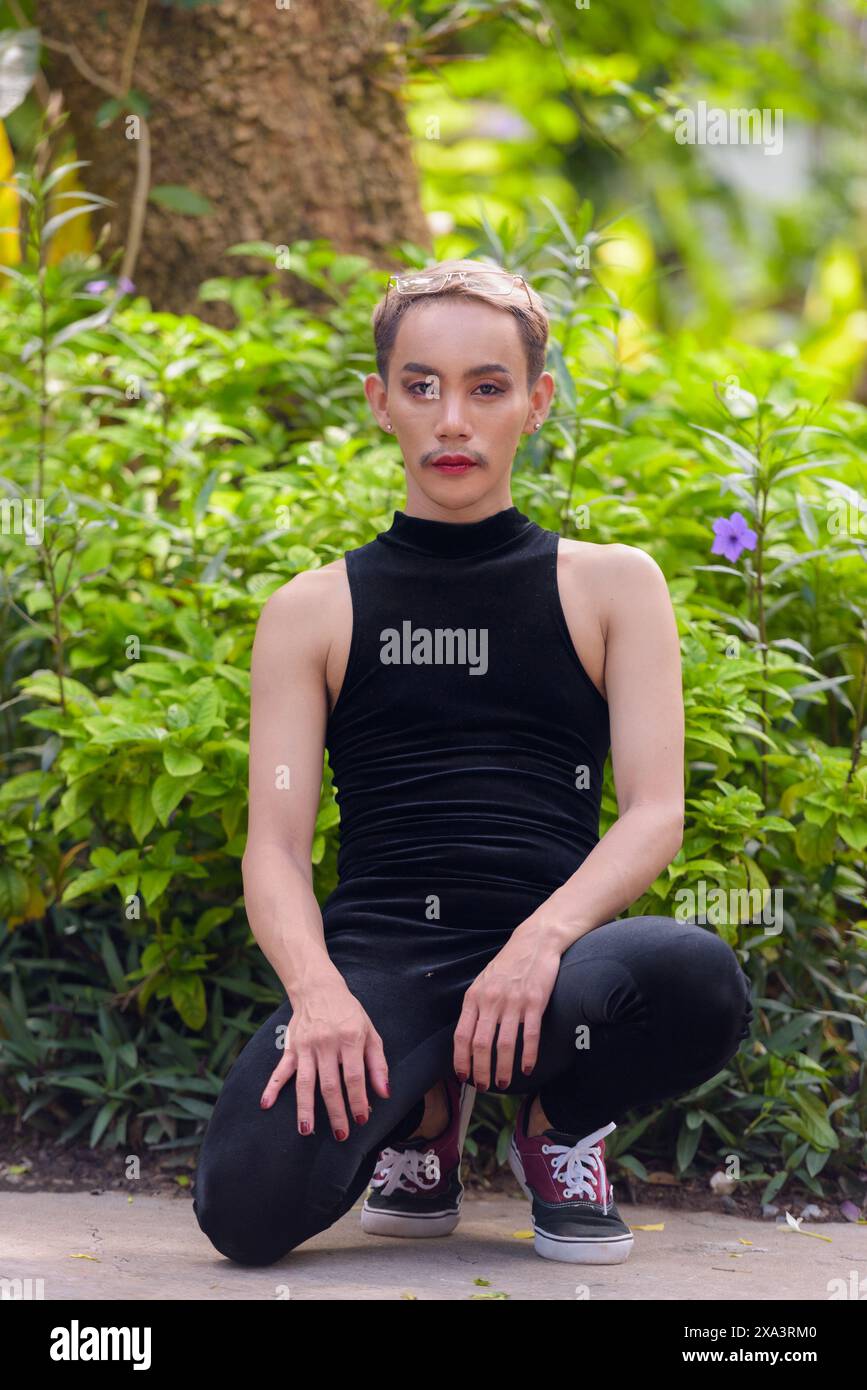 Porträt des schönen asiatischen queeren LGBT Community Unterstützers Mann mit Schnurrbart, der Lippenstift und Jumpsuit trägt Stockfoto