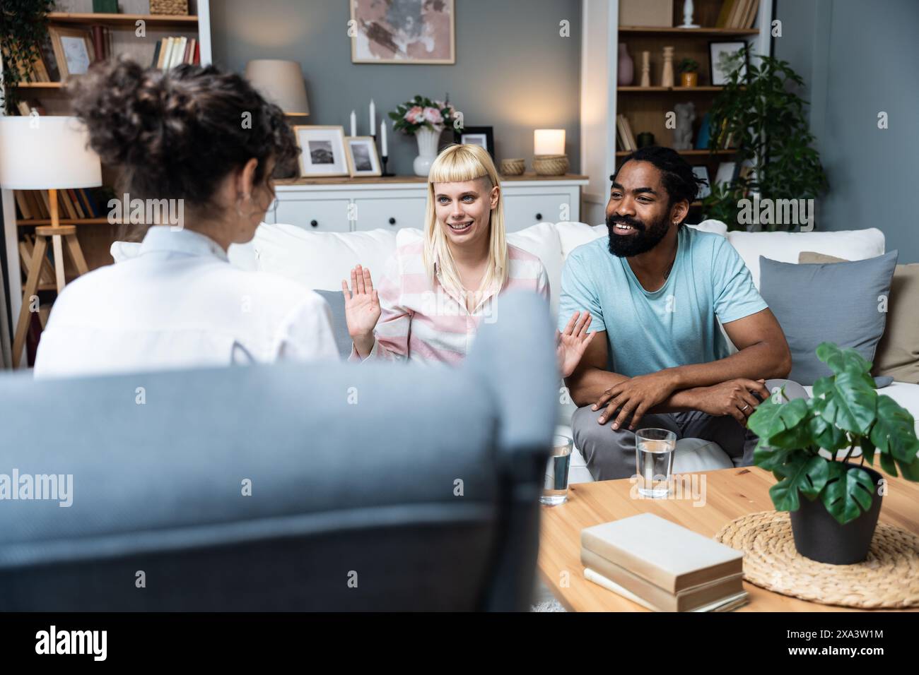 Zwei Leute, junge, vielfältige Paare, die versuchen, Probleme in ihrer Beziehung zu lösen. Multirassische Ehepartner lächeln, während sie sich vor einem Therapeuten in der Th unterhalten Stockfoto