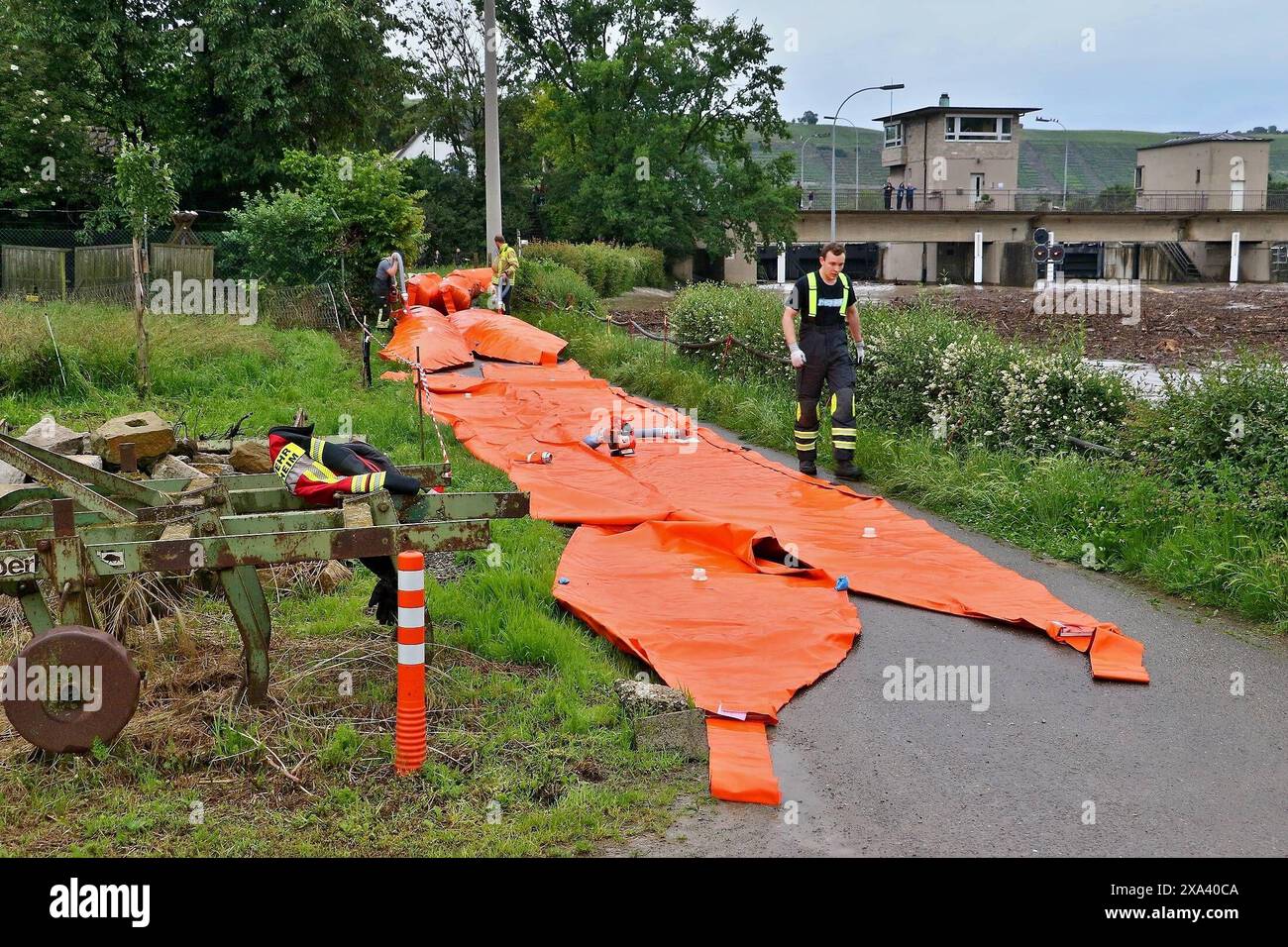 Extreme Neckar-Hochwasser bei Hessigheim - Feuerwehren errichten Schutzdamm mit landkreiseigenem Hochwasserschutzsystem Beaver 01.06.2024: Am Abend des 1.6.2024 erreichte der Neckarpegel bei Hessigheim eine besorgniserregende Höhe. Um die Anwohner zu schützen entschloss sich der Hessigheimer Feuerwehrkommandant gegen 18:30 Uhr eine Komponente des Hochwasserschutzsystems Beaver, welches vom Landkreis Ludwigsburg beschafft wurde, zu alarmieren. Insgesamt wurden rund 400 Meter des Mehrkammerschlauchs beschafft, die alarmierte Freiwillige Feuerwehr Bietigheim-Bissingen rückte mit dem Abrollbehält Stockfoto