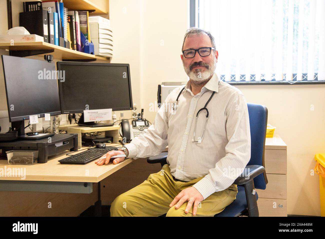 Doktor sitzt an einem Schreibtisch mit einem Computer Stockfoto