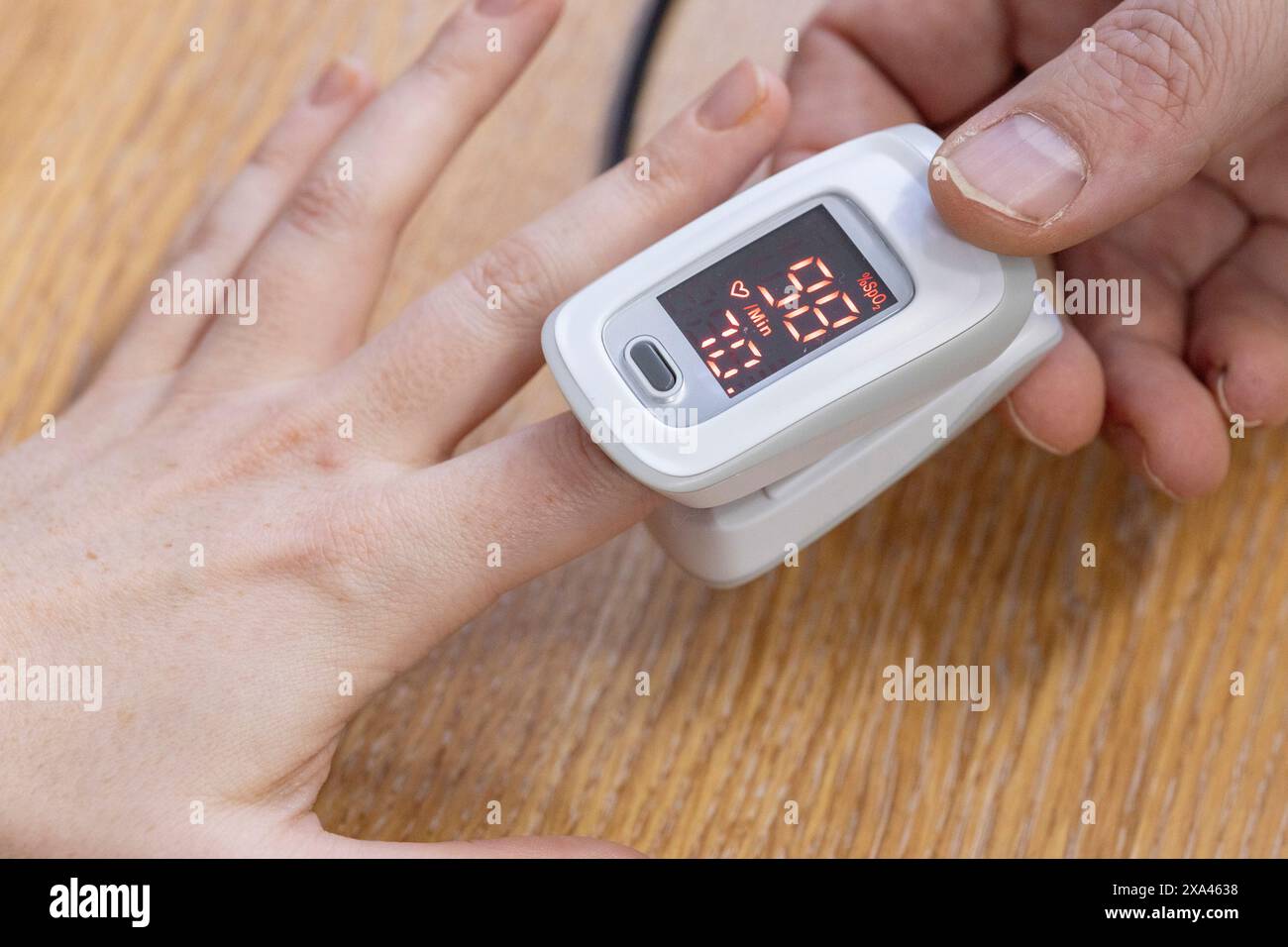 Fingertipp-Pulsoximeter am Finger einer Person. Stockfoto