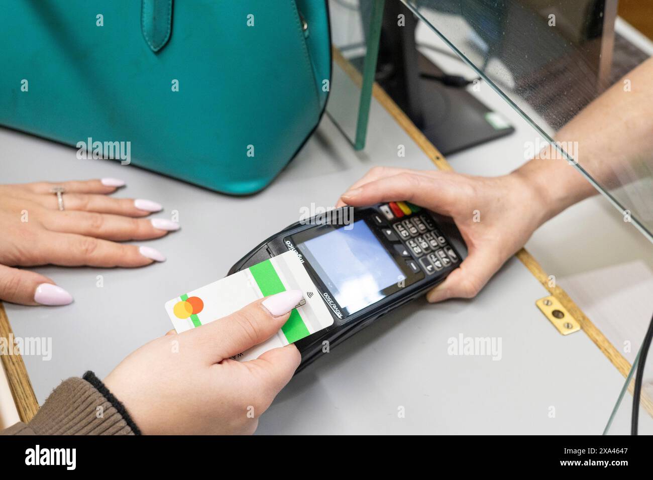 Frau, die kontaktlos an der Rezeption einer Arztpraxis bezahlt Stockfoto