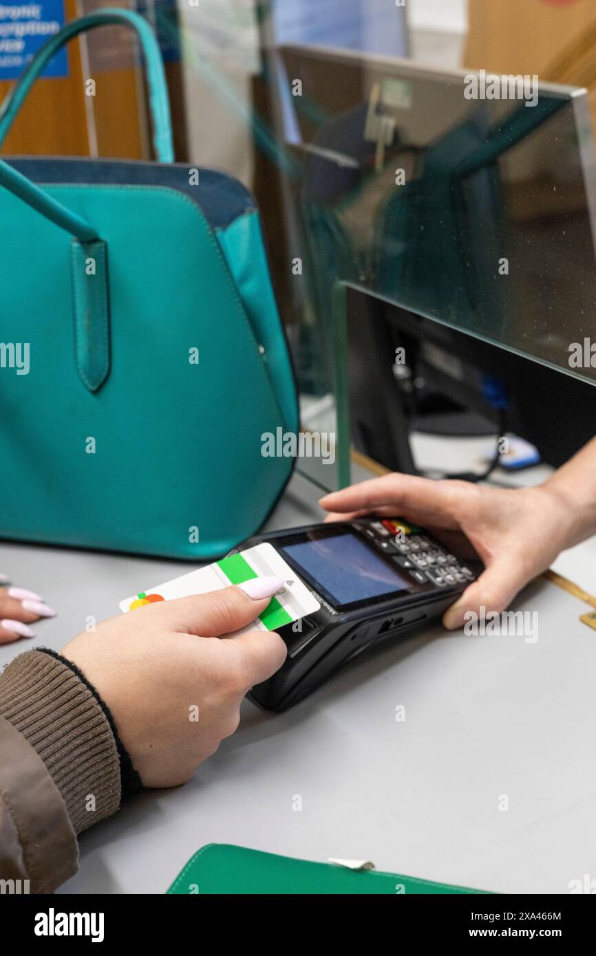 Eine Person, die eine Zahlung an einer Rezeption eines Krankenhauses leistet Stockfoto