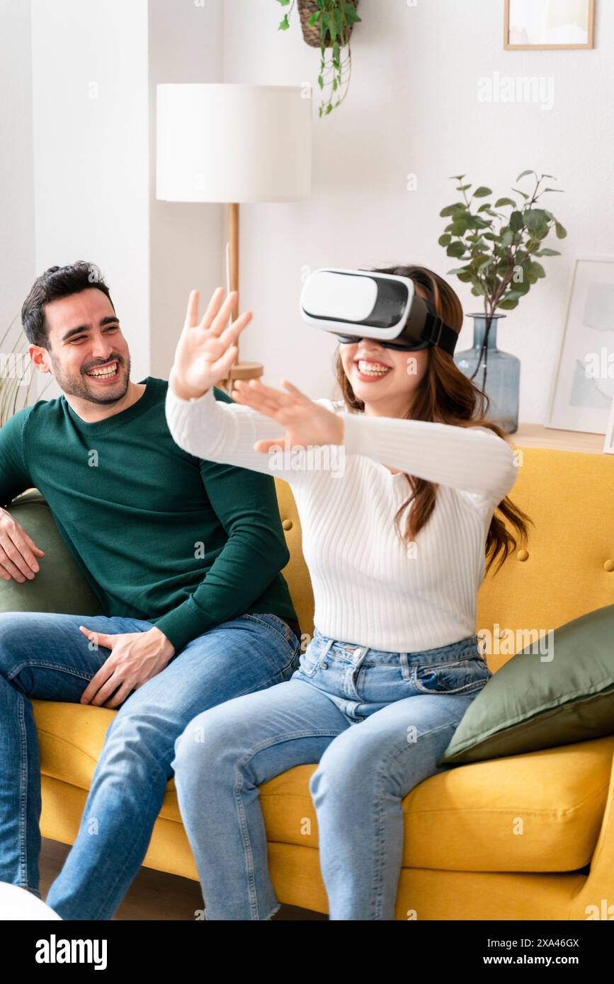 Die Frau verwendet das VR-Headset mit einem Mann auf dem Sofa Stockfoto