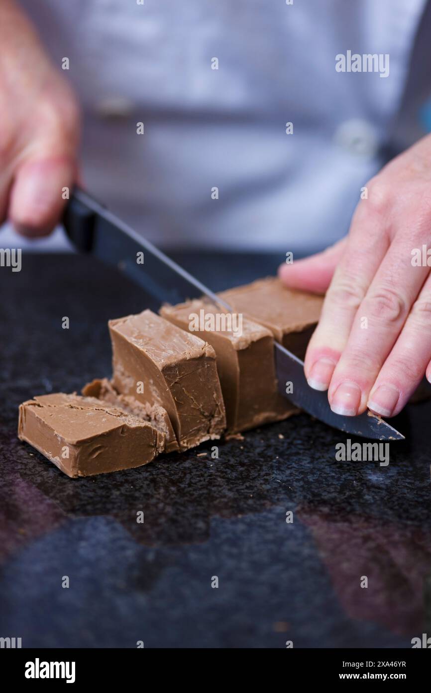 Nahaufnahme eines Chefs Hände schneiden Schokolade block Stockfoto