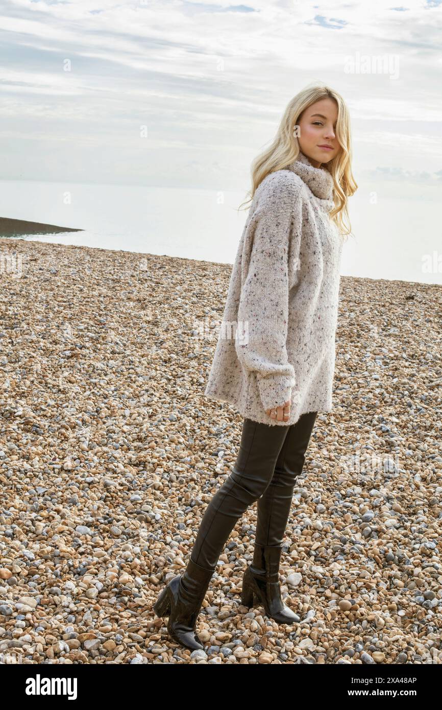 Junge Frau im Winter am Kiesel-Strand Stockfoto