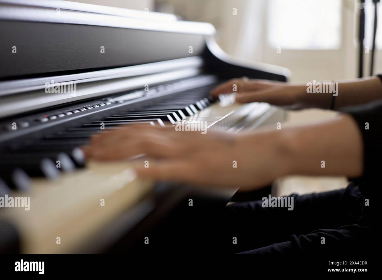 Eine Person spielt Klavier und konzentriert sich dabei auf die Hände, die sich über die schwarzen und weißen Tasten bewegen. Stockfoto