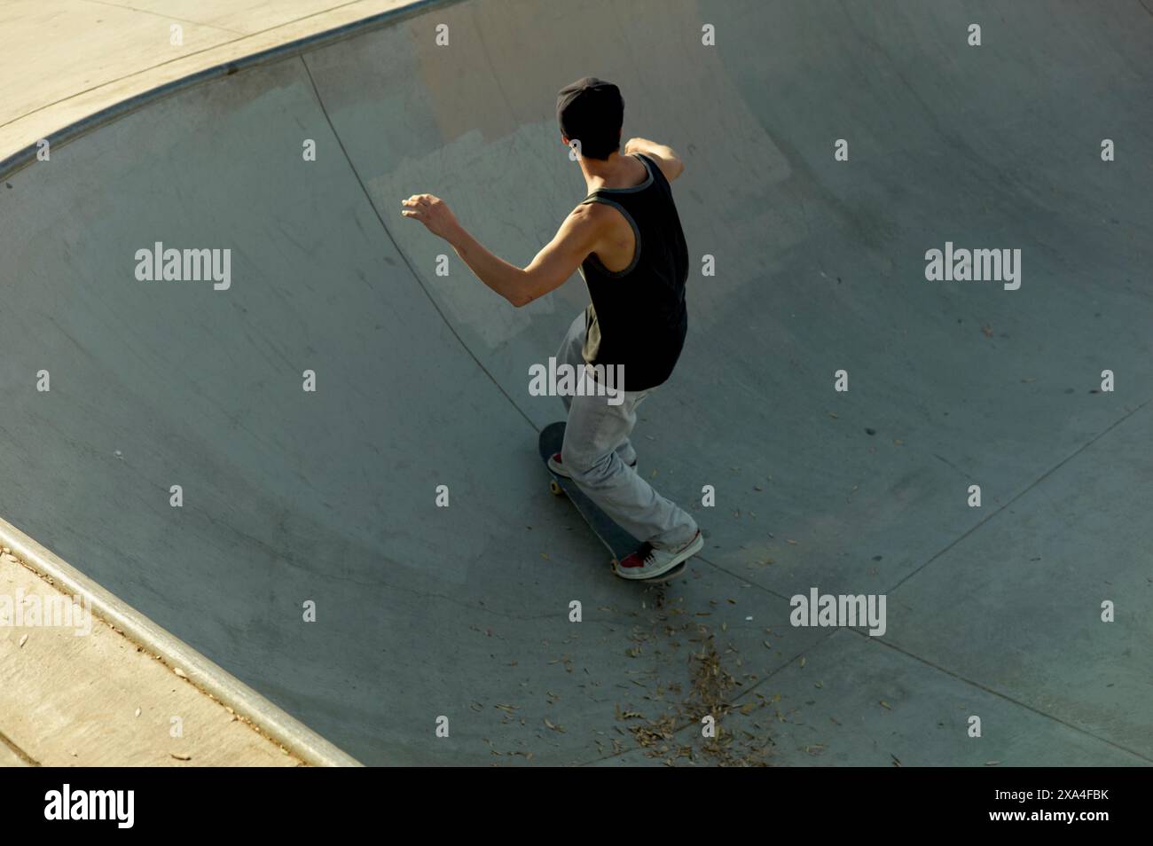 Ein Skateboarder reitet entlang der Kurve einer Skateboarde und bereitet sich auf ein Manöver vor. Stockfoto