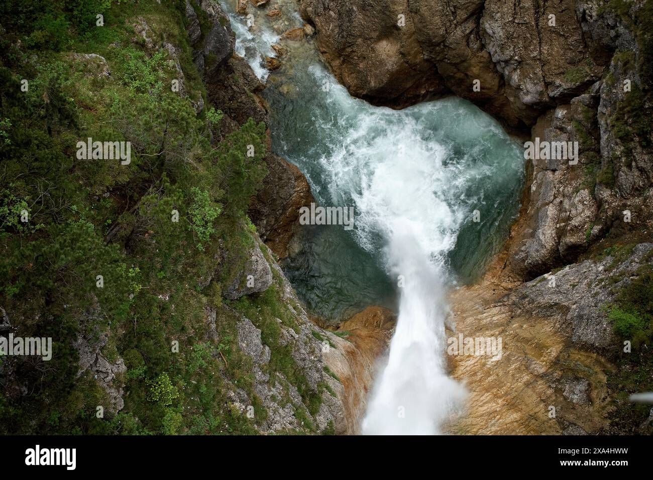 Ein Blick aus der Luft auf einen turbulenten Fluss, der durch eine enge felsige Schlucht mit üppigem Grün an den Seiten verläuft. Stockfoto