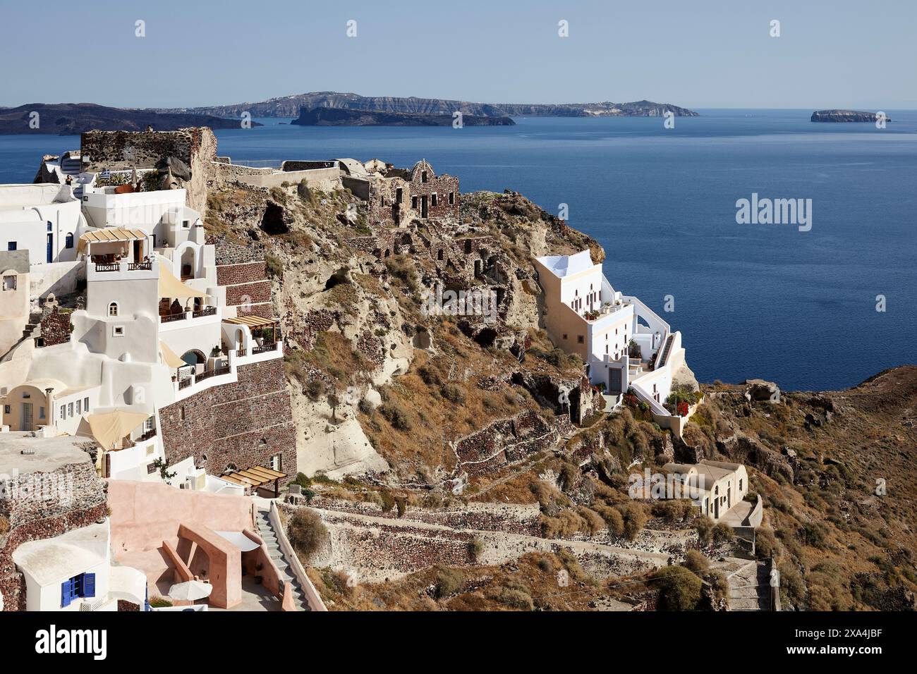 Ein malerischer Blick auf die weiß getünchten Gebäude von Oia auf der Insel Santorin, Griechenland, mit Blick auf die Ägäis mit Klippen und Inseln in der Ferne. Stockfoto
