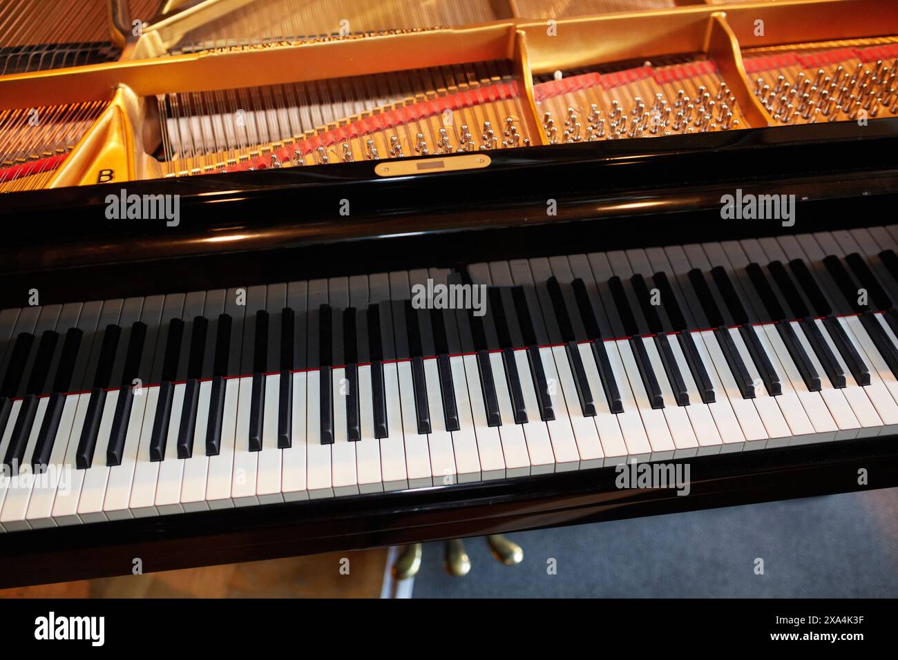 Das Bild zeigt eine Nahaufnahme des offenen Deckels eines Flügels mit schwarz-weißen Tasten, Saiten und Innenmechanismus. Stockfoto