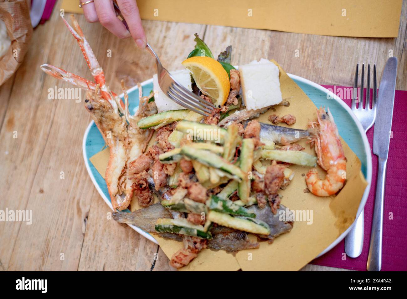 Frische Meeresfrüchte-Platte mit Zucchini und Zitrone auf einem lebendigen Teller. Stockfoto