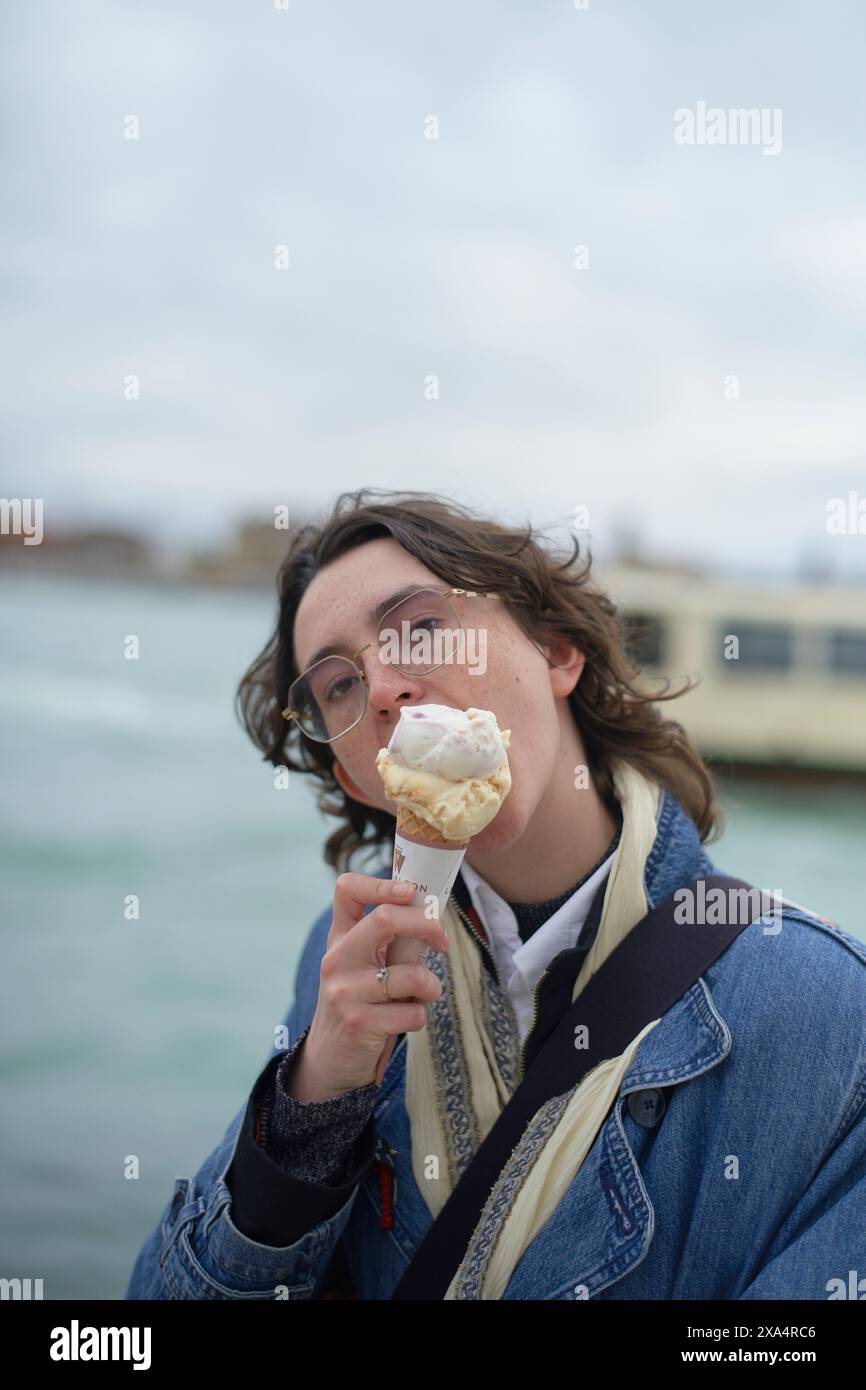 Junger Erwachsener, der eine Eiscreme am Wasser genießt. Stockfoto