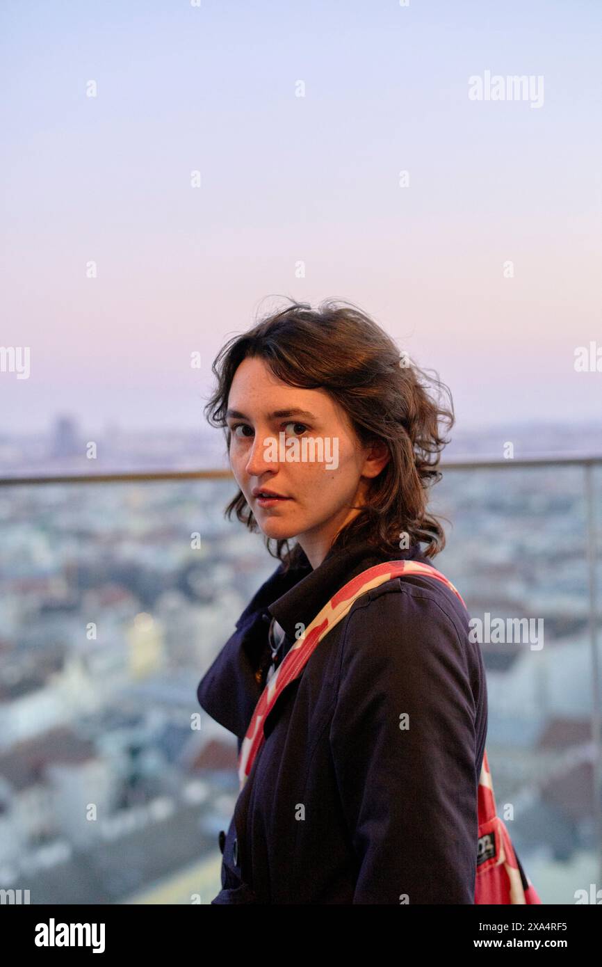 Frau mit besinnlichem Blick auf die Stadt in der Abenddämmerung Stockfoto