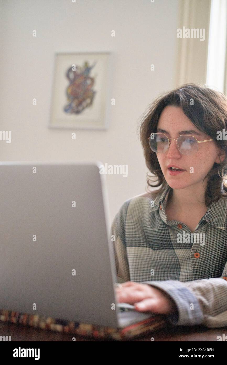 Junger Erwachsener, der intensiv an einem Laptop in einem Zuhause arbeitet Stockfoto