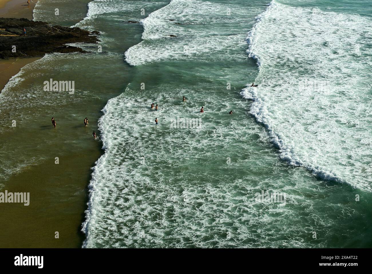Aus der Vogelperspektive auf Schwimmer, die die Wellen an einem sonnigen Strand genießen. Stockfoto
