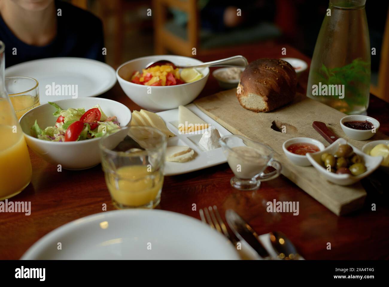 Ein frisches kontinentales Frühstück mit einer Auswahl an Speisen wie Brot, Salat, Obst und Getränken auf einem Holztisch. Stockfoto