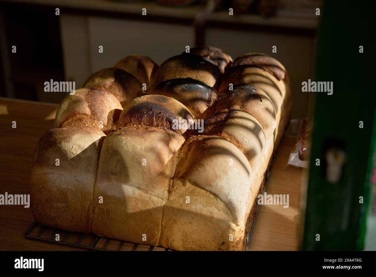 Frisch gebackene Brotlaibe, die auf einem Gitterrost bei warmem Sonnenlicht gekühlt werden. Stockfoto