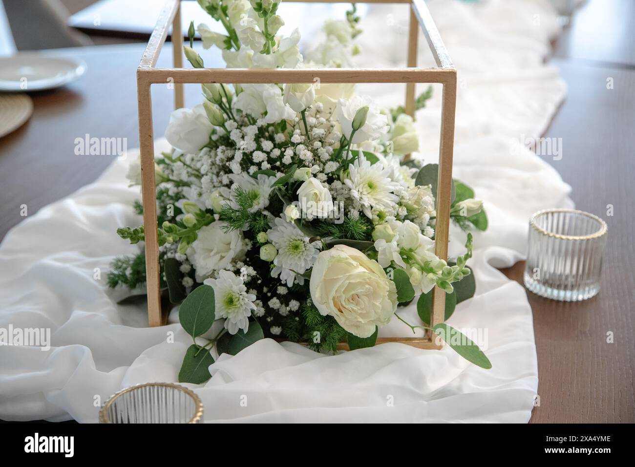 Ein wunderschöner Blumenaufsatz mit weißen Rosen, Gänseblümchen, gypsophila und Grün, elegant in einem Holzrahmen angeordnet Stockfoto