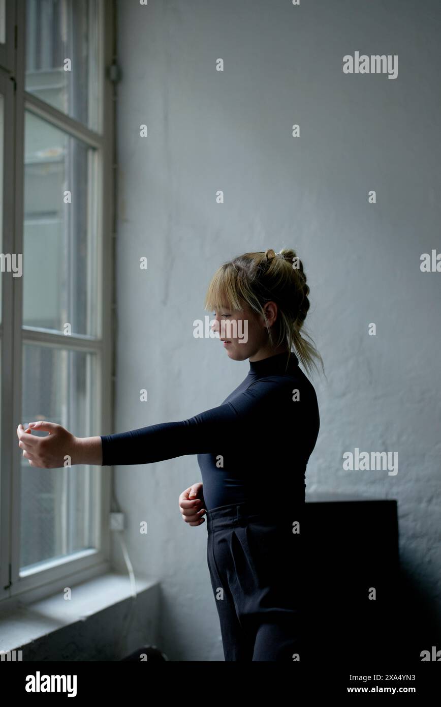 Frau in einer Tanzpose am Fenster mit natürlichem Licht. Stockfoto