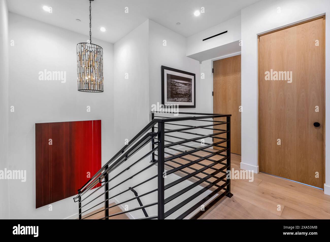 Moderne Holztreppe mit elegantem schwarzem Geländer und weißen Wänden in stilvollem Eingangsbereich Stockfoto