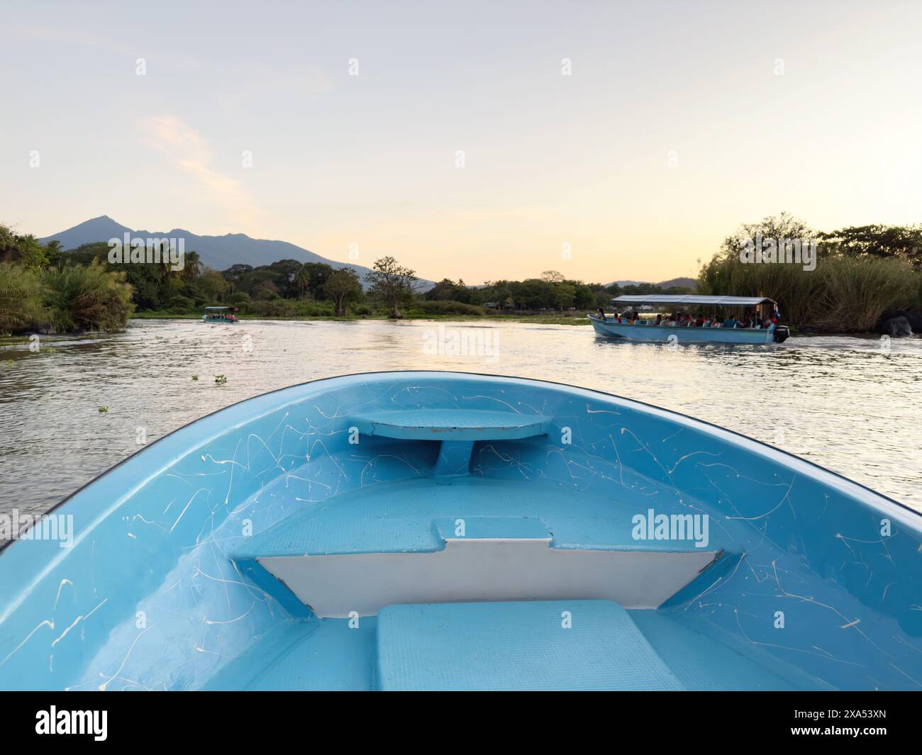 Bootstour auf dem See mit vulkanischem Hintergrund bei Sonnenuntergang Stockfoto