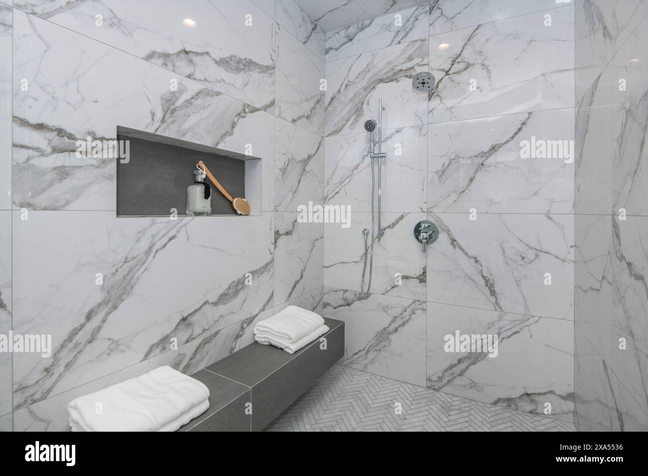Eine moderne Dusche mit weißen Handtüchern und einem stehenden Duschkopf Stockfoto