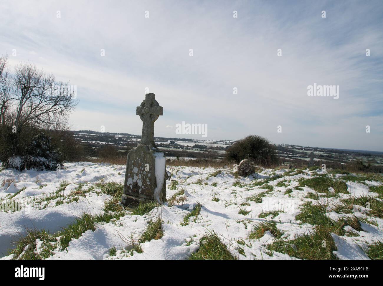 Ein Grab und ein Kreuz im Schnee am Rand des Friedhofs Stockfoto