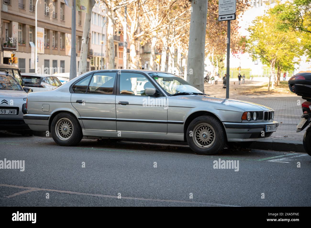 Ein altes Premium-Auto der BMW 520i 5er Generation E34 in silberfarbener Farbe parkt auf der Straße von Barcelona Stockfoto