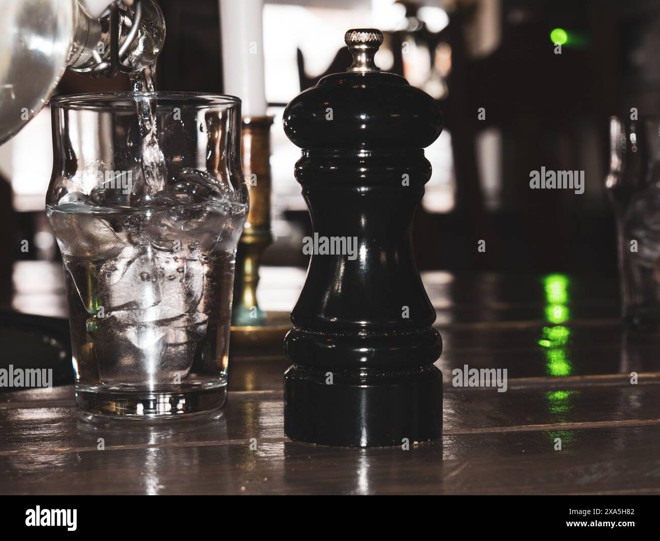 Eine Pfeffermühle auf einem Tisch, umgeben von verschiedenen Getränken in Gläsern Stockfoto