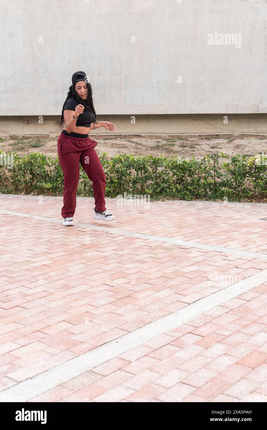 Junge Frau in lässiger Sportkleidung, die im Freien Hip-Hop-Tanz spielt. Stockfoto