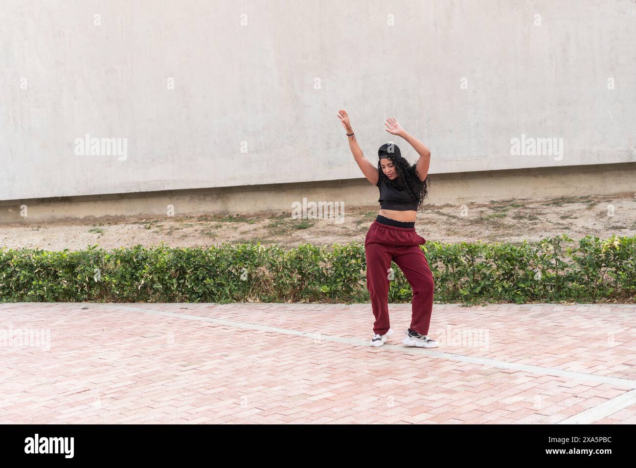 Junge Frau in sportlicher Freizeitkleidung, die Hip-Hop-Tanz macht, bewegt sich draußen. Stockfoto