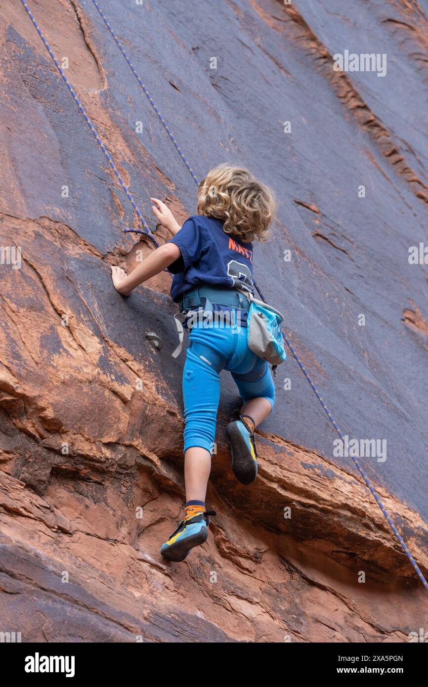 Ein kleiner Junge im Alter von 6 Jahren, der im Hunter Canyon in der Nähe von Moab, Utah, Klettern lernt. Stockfoto