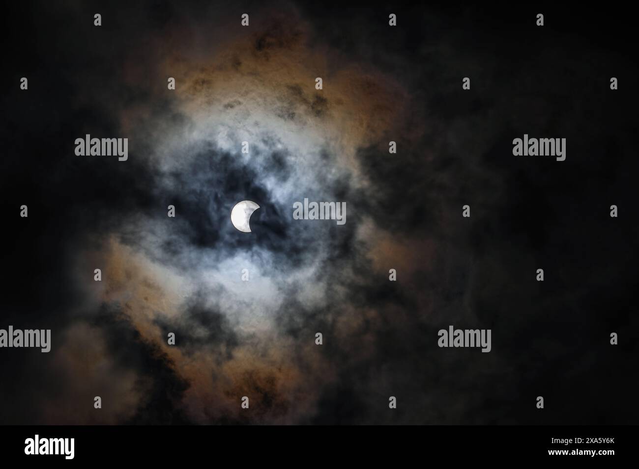 Die Sonnenfinsternis mit dem Mond, der durch dunkle Wolken in Waco, Texas scheint Stockfoto