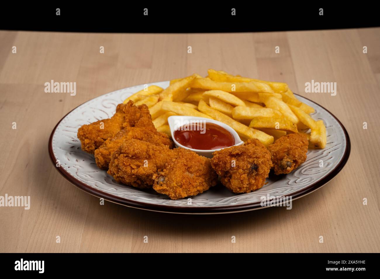 Ein Blick von oben auf knusprige Pommes frites und Hähnchenbrötchen mit Ketchup auf einem weißen Teller Stockfoto