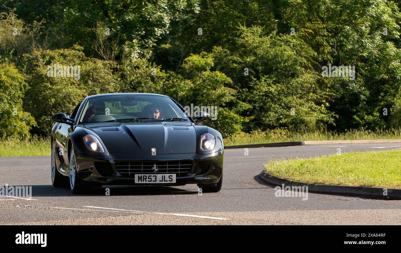 Stony Stratford, UK - 2. Juni 2024: 2008 schwarzer Ferrari 599 Auto fährt auf einer britischen Landstraße Stockfoto