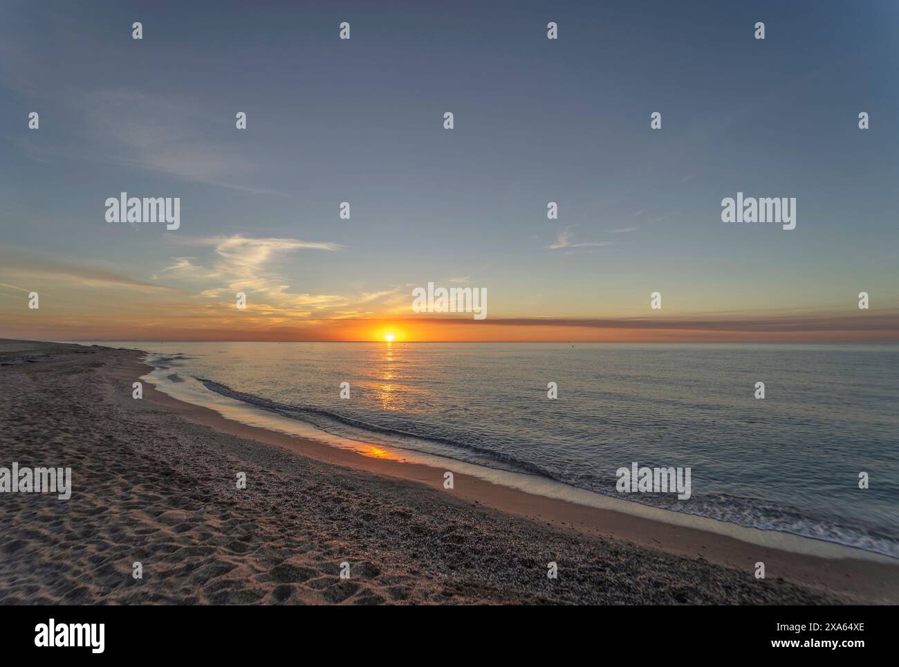 Der Sonnenaufgang am Strand von Mojacar wird mit einem goldenen Himmel und den Sonnenstrahlen auf dem Meer präsentiert. Der Strand, von feinem Sand und brauner Farbe. Stockfoto