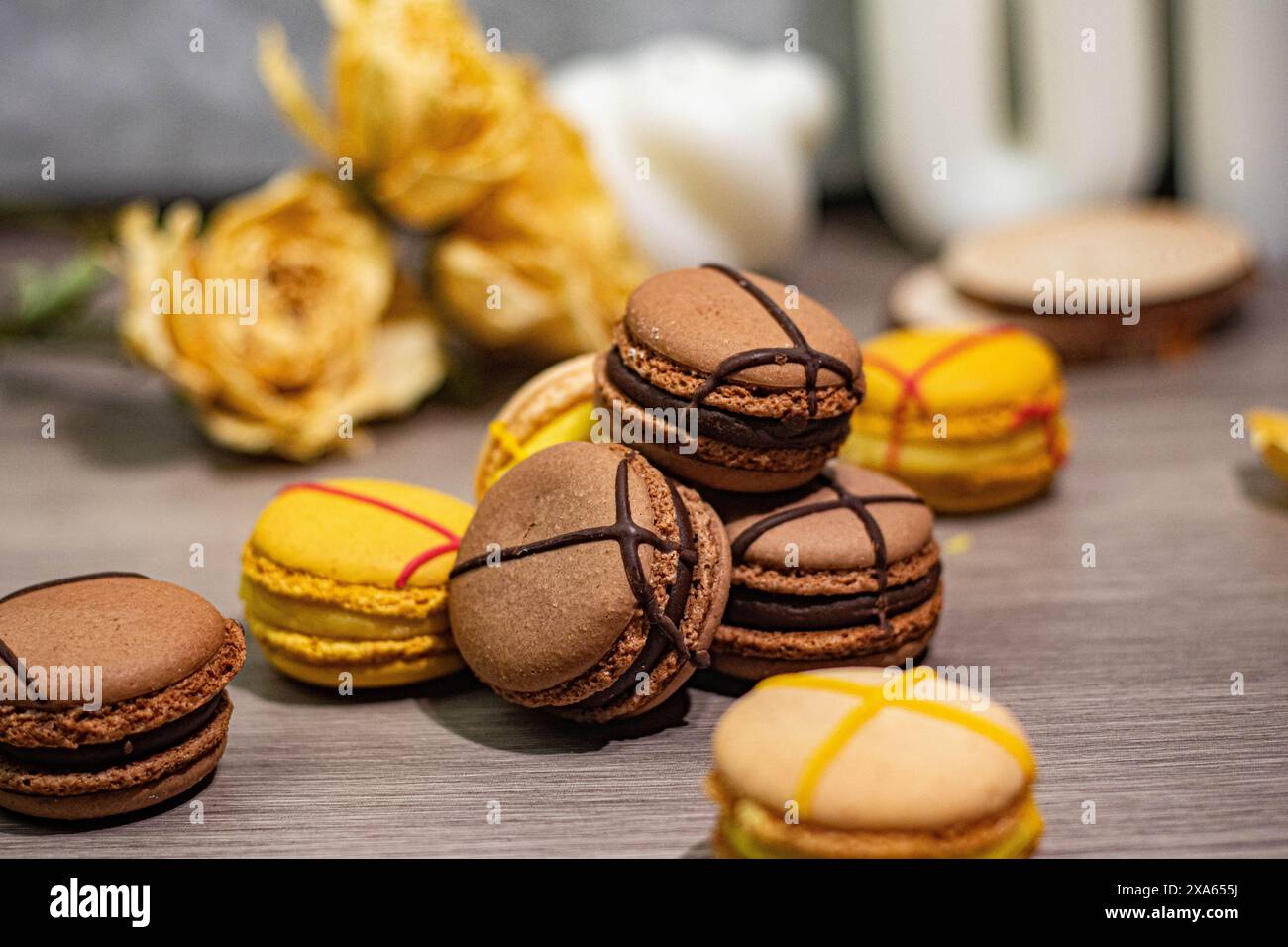 Die farbenfrohen Macarons und zarten Rosen sind auf einem Tisch angeordnet Stockfoto