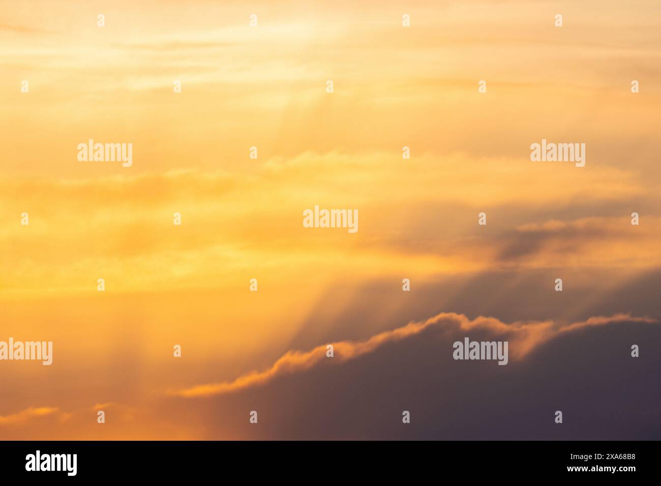 Ein leuchtender orangefarbener Sonnenuntergangshimmel mit flauschigen Wolken Stockfoto