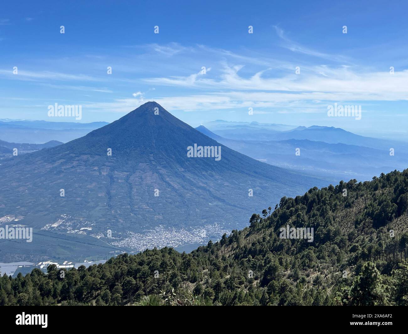 Ein hoher Berg, der über Bäumen auf einem Hügel thront Stockfoto