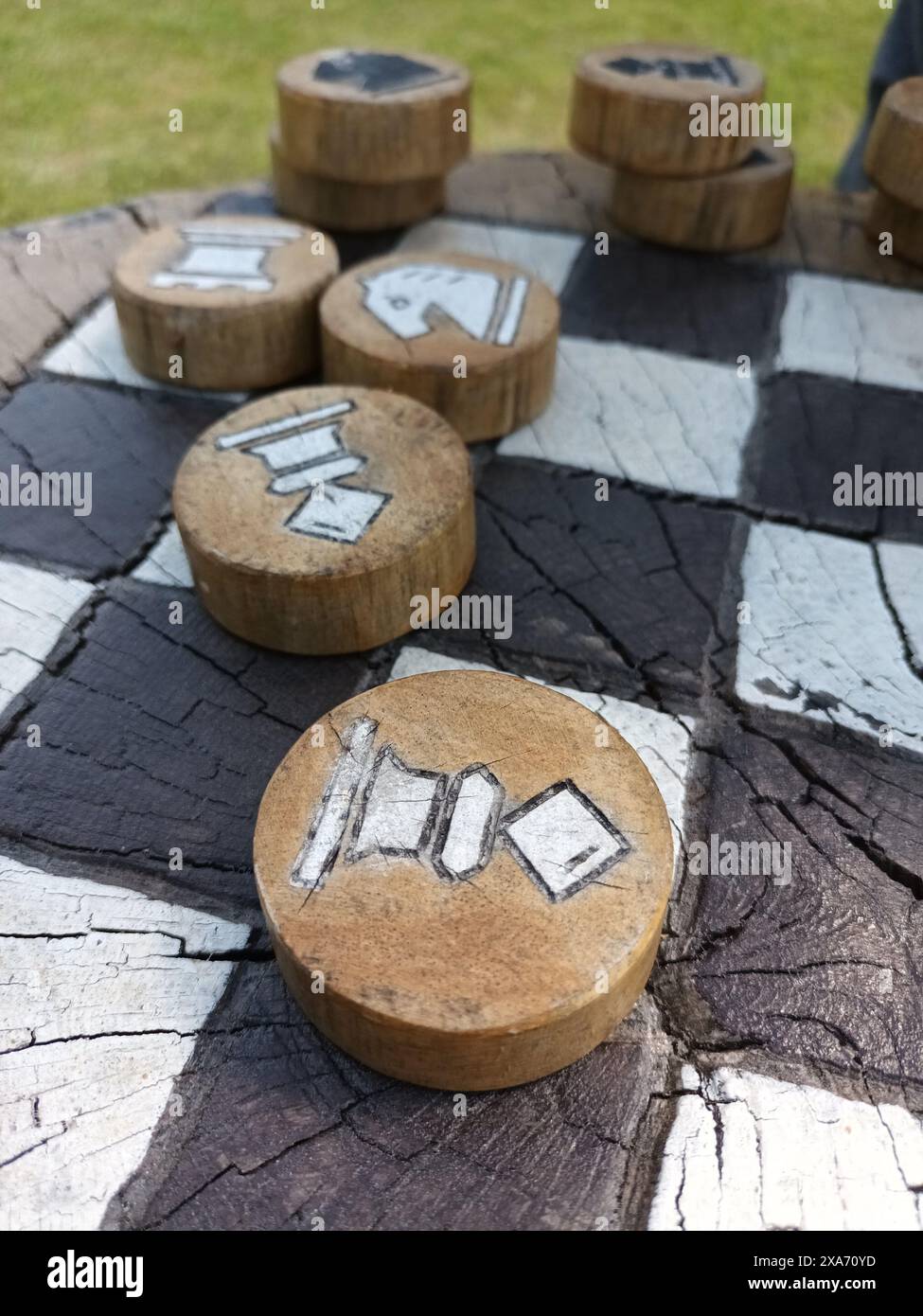 Einige Schachstücke aus Holz werden draußen auf einem großen Brett platziert Stockfoto
