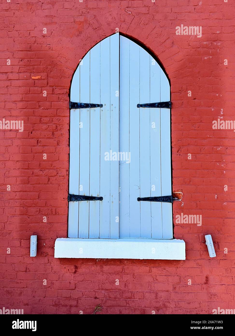 Die geschlossenen blauen Holzläden eines Fensters in einer hellroten Backsteinwand des Fisgard Lighthouse, Victoria, BC. Stockfoto