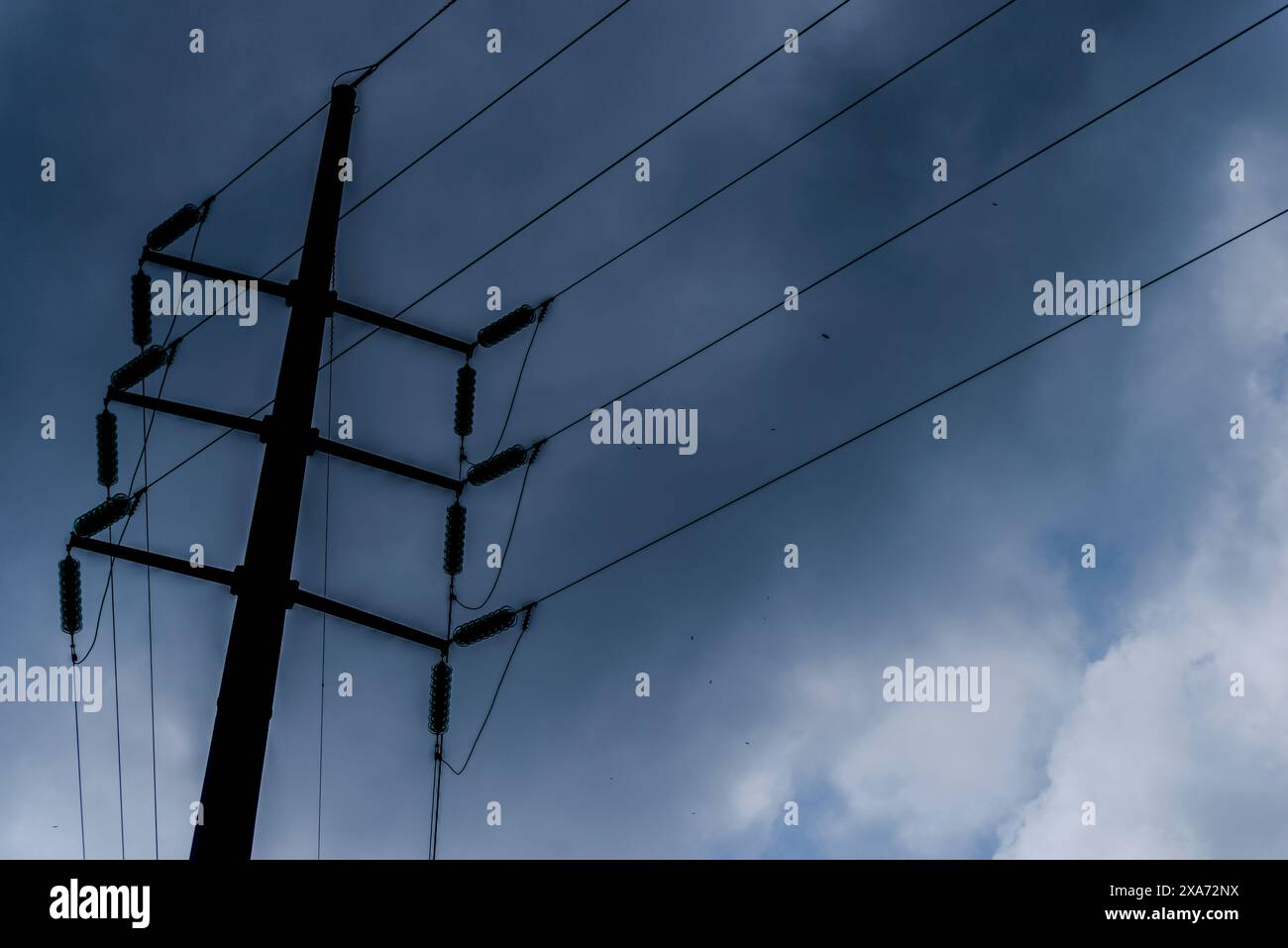 Drei Drähte an einem Stab gegen bewölkten Himmel Stockfoto