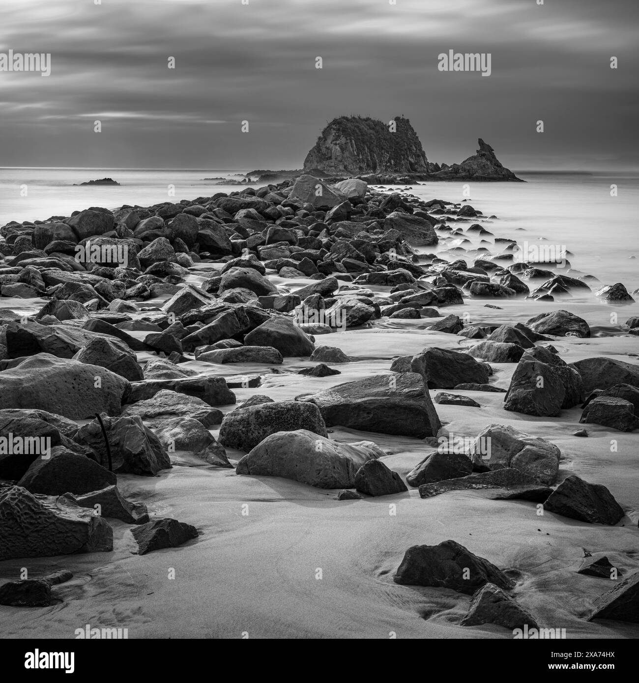 Schwarzweißbild des Groyne am Omah Beach im Norden von Auckland Stockfoto