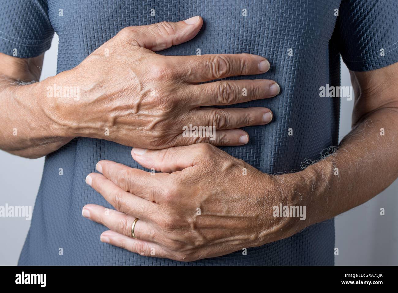 Eine Nahaufnahme eines Mannes mit Händen über dem Bauch Stockfoto