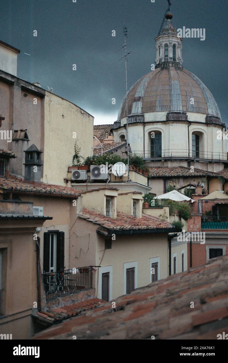 Ein Gebäude in der Nähe der Kirchenkuppel mit zwei Satellitenschüsseln in Rom Stockfoto