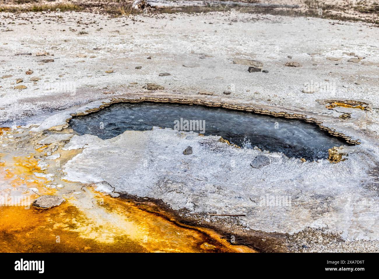 Eine orangene Substanz durch Felsen im Wasser Stockfoto